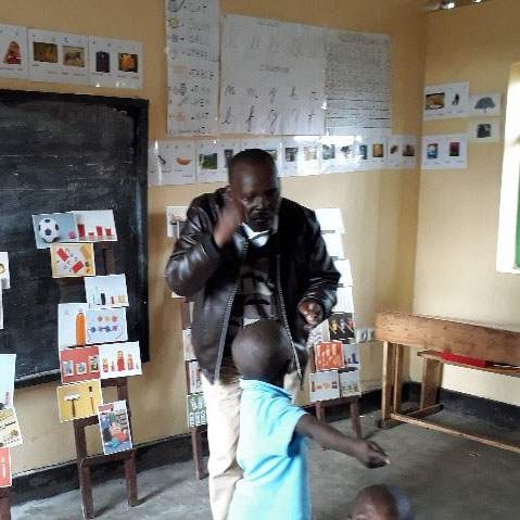 Louis in one of the new classrooms, explaining something in sign to one of the children.